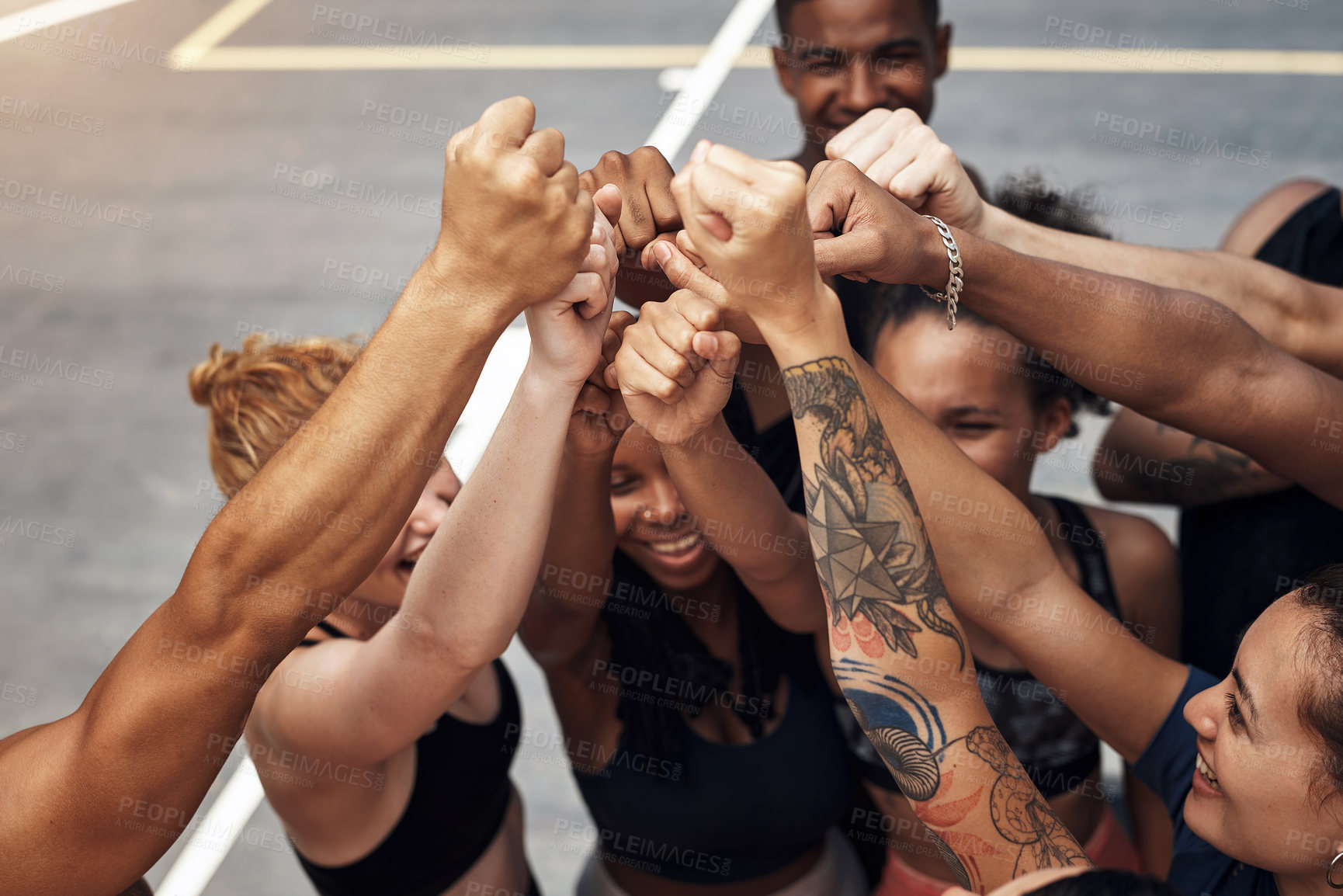 Buy stock photo Shot of a group of sporty young people standing together in a huddle on a basketball court