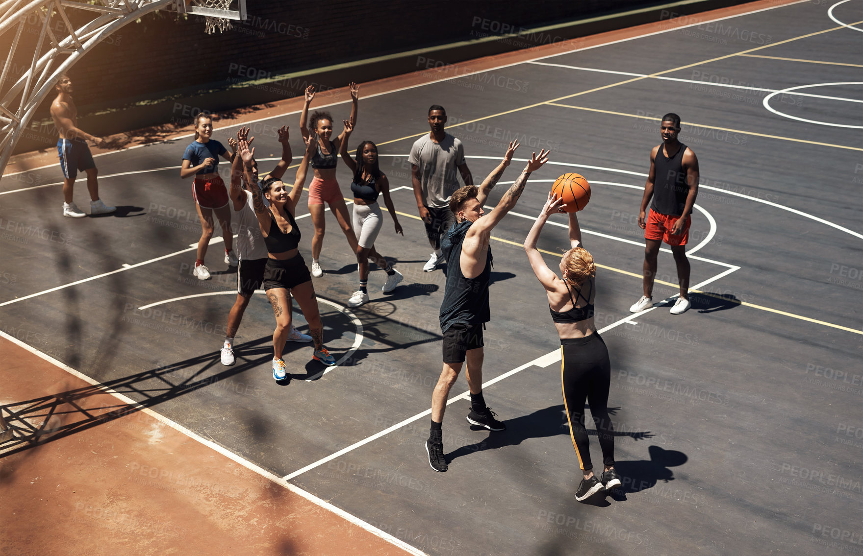 Buy stock photo Shot of a group of sporty young people playing basketball on a sports court