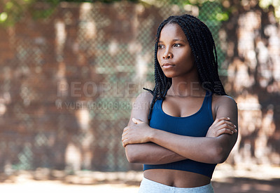 Buy stock photo Cropped shot of an attractive young female athlete standing with her arms folded on the basketball court