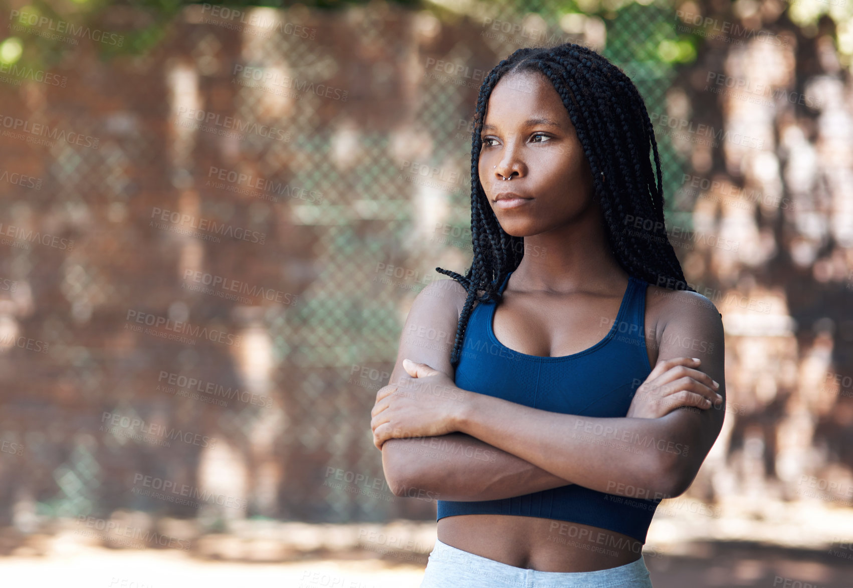 Buy stock photo Cropped shot of an attractive young female athlete standing with her arms folded on the basketball court