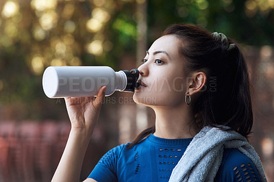 Buy stock photo Cropped shot of an attractive young female athlete drinking water while standing on the basketball court