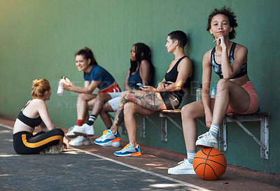 Buy stock photo Full length portrait of an attractive young female athlete sitting on a bench at the basketball court with her teammates in the background