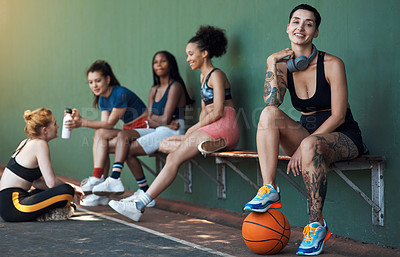 Buy stock photo Full length portrait of an attractive young female athlete sitting on a bench at the basketball court with her teammates in the background