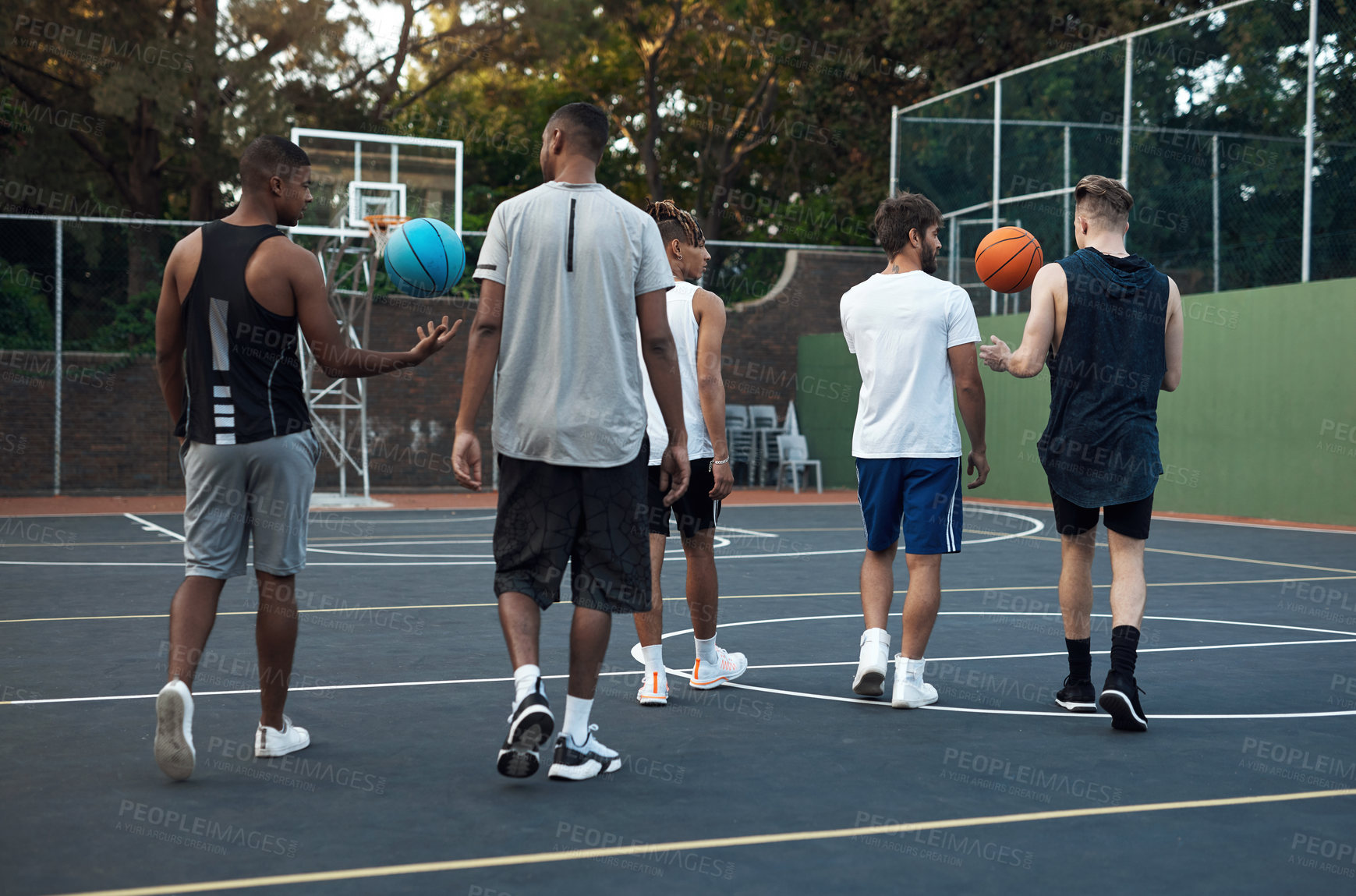 Buy stock photo Rearview shot of a group of sporty young men hanging out on a basketball court