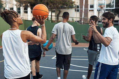 Buy stock photo Rearview shot of a group of sporty young men hanging out on a basketball court