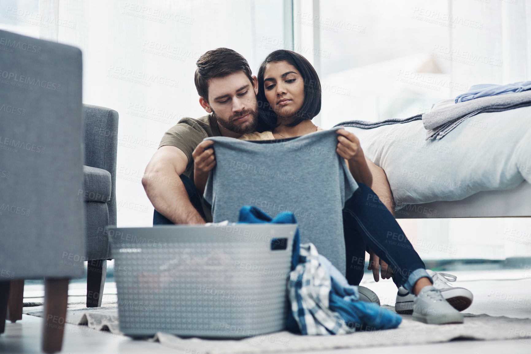 Buy stock photo Shot of an affectionate young couple doing laundry together at home
