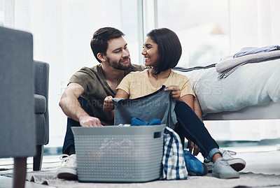 Buy stock photo Shot of a happy young couple doing laundry together at home