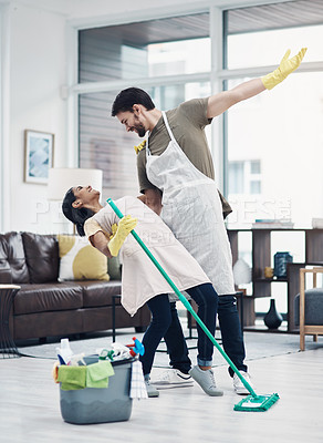 Buy stock photo Shot of a happy young couple dancing while mopping the floor at home
