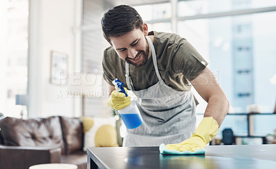 Buy stock photo Shot of a young man disinfecting a table at home
