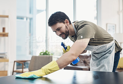 Buy stock photo Shot of a young man disinfecting a table at home
