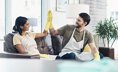 Buy stock photo Shot of a happy young couple giving each other a high five after cleaning their home together