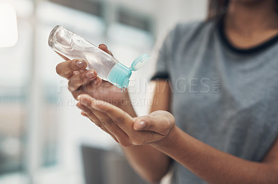 Buy stock photo Shot of an unrecognisable woman disinfecting her hands with sanitiser at home