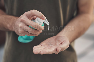 Buy stock photo Shot of an unrecognisable man disinfecting his hands with sanitiser at home