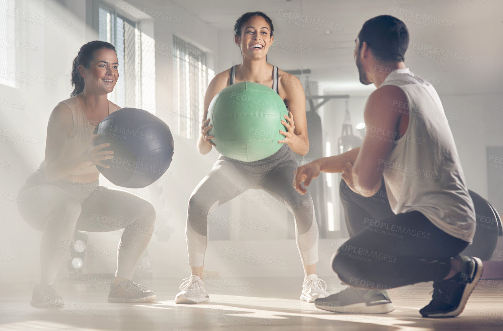 Buy stock photo Shot of two women using fitness balls while working out with their trainer