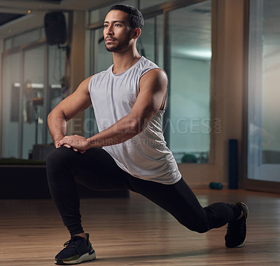 Buy stock photo Full length shot of a handsome young male athlete doing lunges in the gym