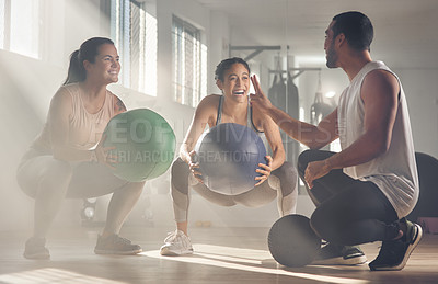 Buy stock photo Shot of two women using fitness balls while working out with their trainer