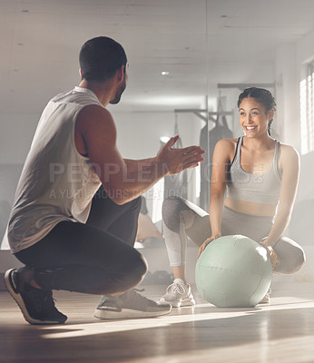 Buy stock photo Shot of a woman using a exercise ball while working out with a personal trainer