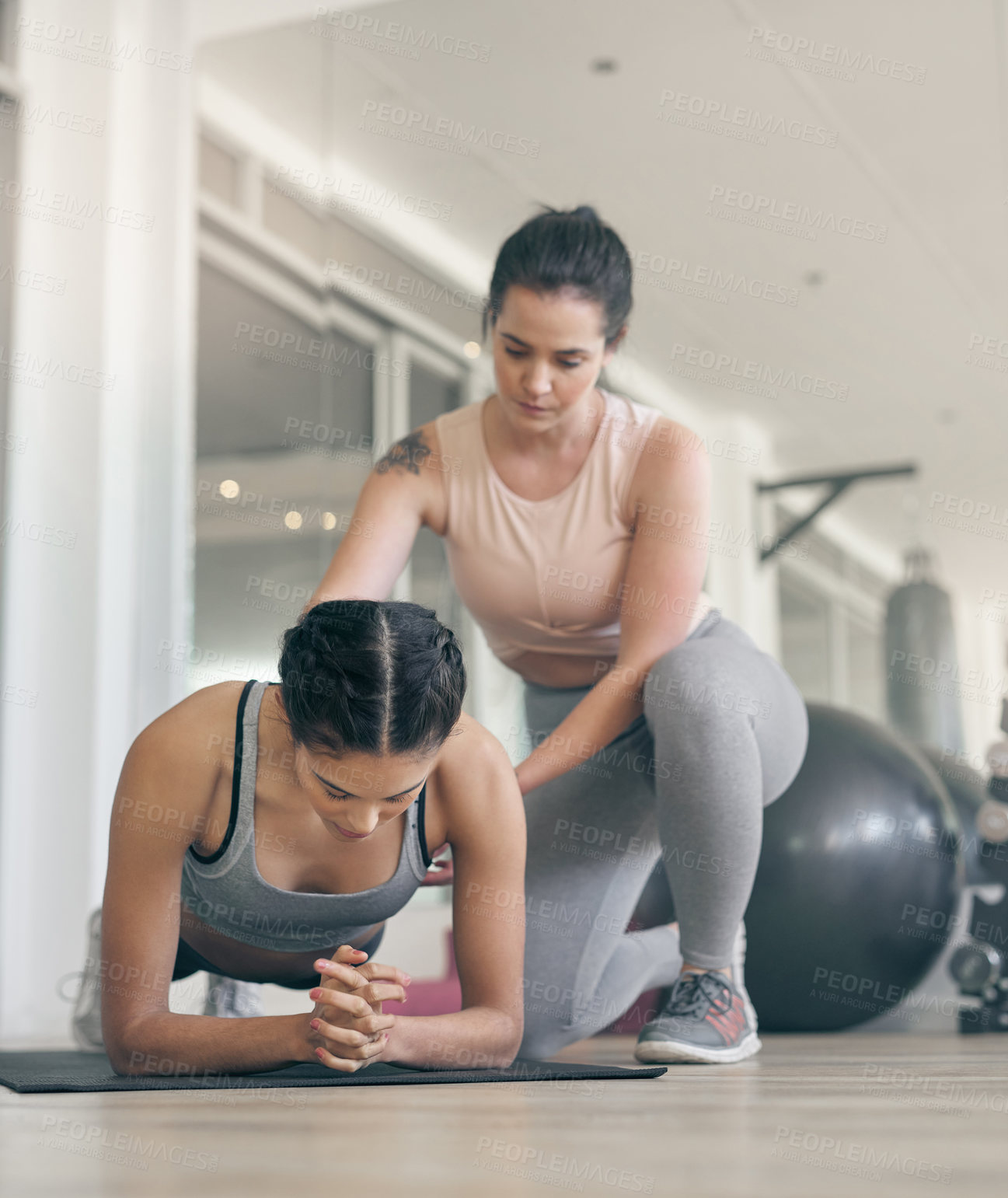 Buy stock photo Shot of a young woman working out with a personal trainer at the gym