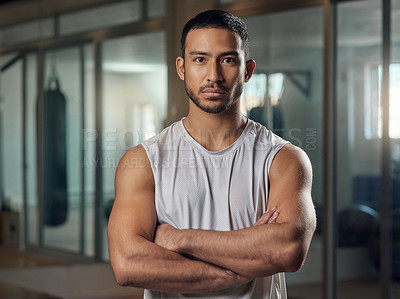 Buy stock photo Cropped portrait of a handsome young male athlete standing with his arms crossed in the gym