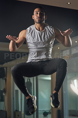 Buy stock photo Full length shot of a handsome young male athlete jumping during his workout in the gym
