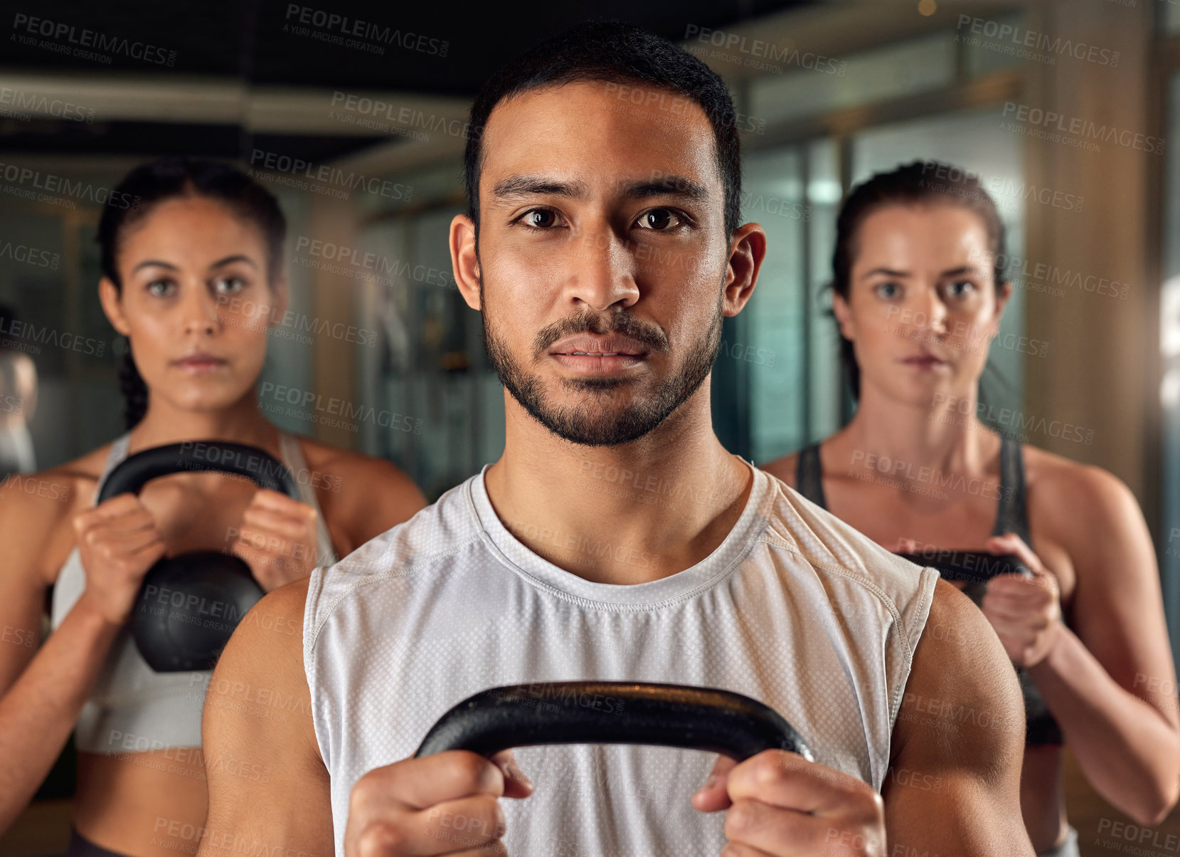 Buy stock photo Cropped portrait of three young athletes working out with kettle bells in the gym