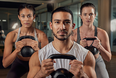Buy stock photo Cropped portrait of three young athletes working out with kettle bells in the gym