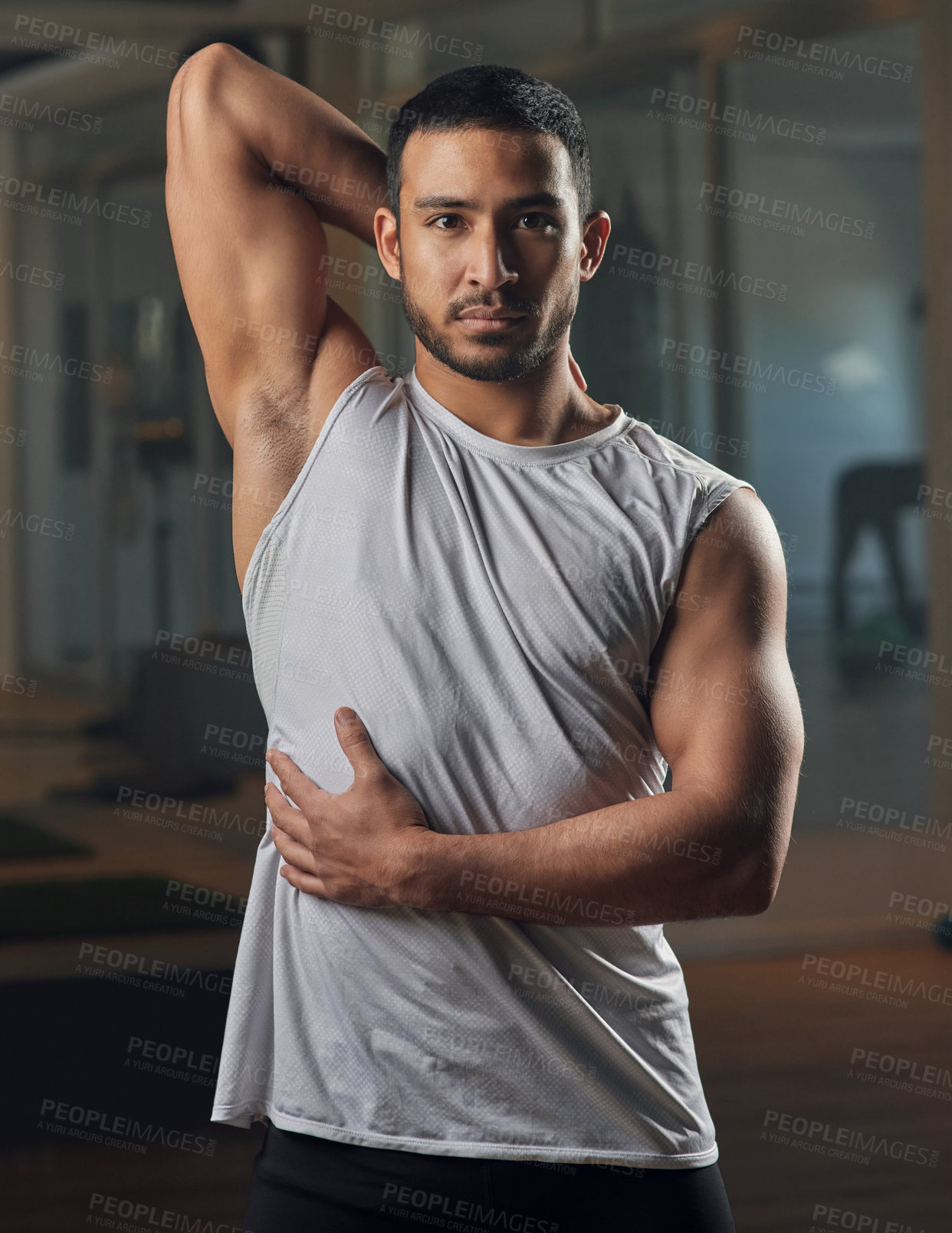 Buy stock photo Cropped portrait of a handsome young male athlete stretching in the gym