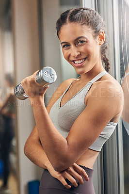 Buy stock photo Cropped portrait of an attractive young female athlete working out with a dumbbell in the gym