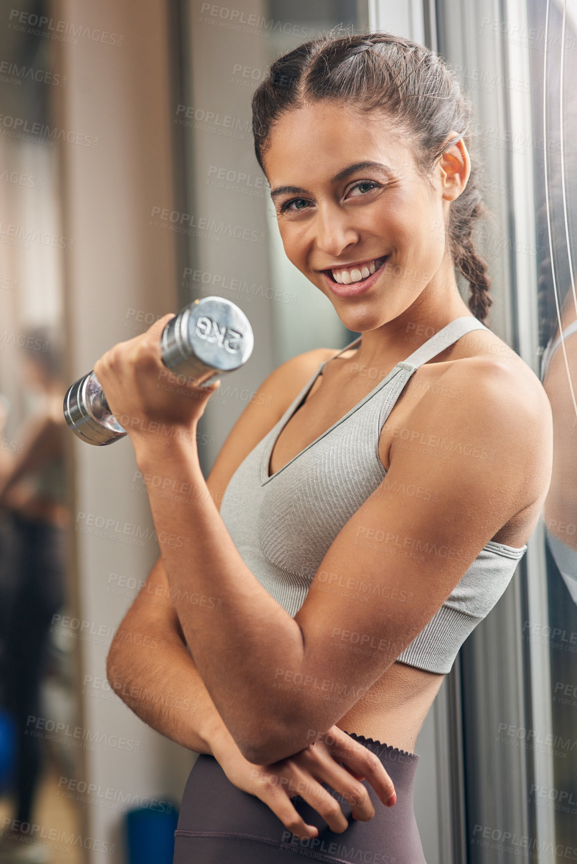 Buy stock photo Cropped portrait of an attractive young female athlete working out with a dumbbell in the gym