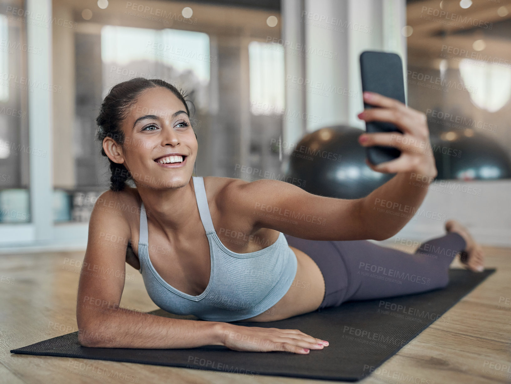 Buy stock photo Full length shot of an attractive young female athlete taking selfies in the gym