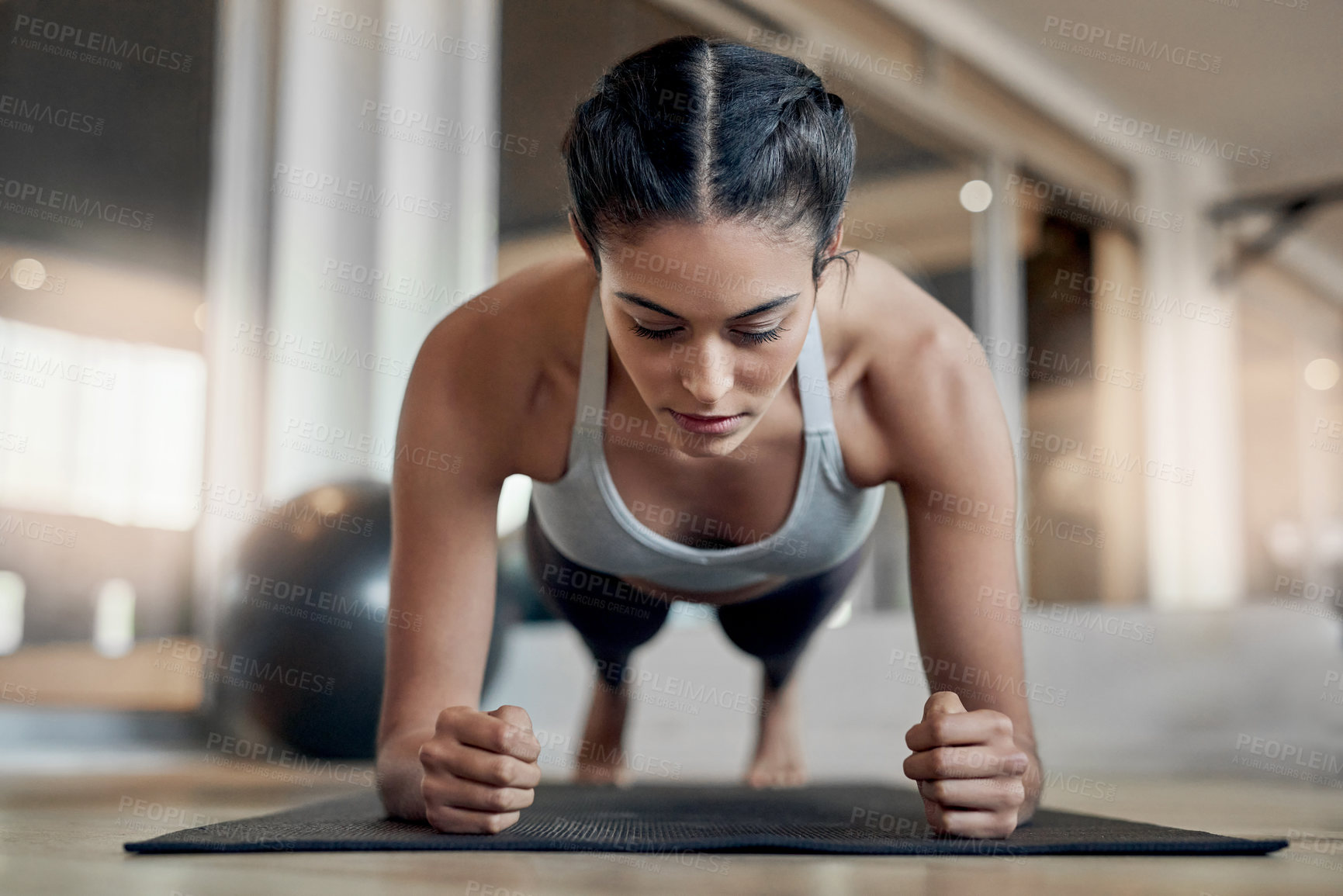 Buy stock photo Full length shot of an attractive young female athlete planking in the gym