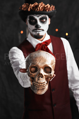 Buy stock photo Cropped portrait of a handsome young man dressed in his Mexican-style halloween costume holding out a skull