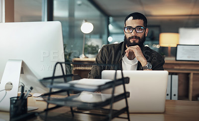 Buy stock photo Shot of a young businessman using a laptop during a late night in a modern office