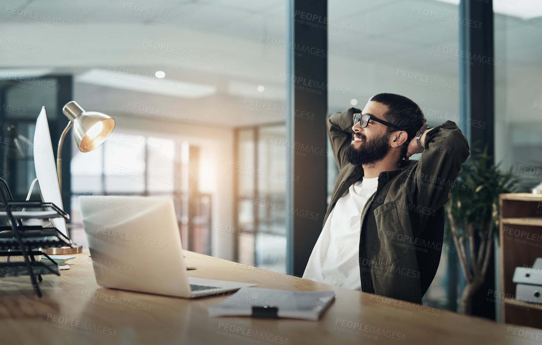 Buy stock photo Shot of a young businessman taking a break while working late at night in a modern office