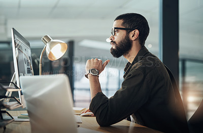 Buy stock photo Shot of a young businessman using a computer during a late night in a modern office