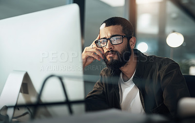 Buy stock photo Shot of a young businessman using a computer during a late night in a modern office