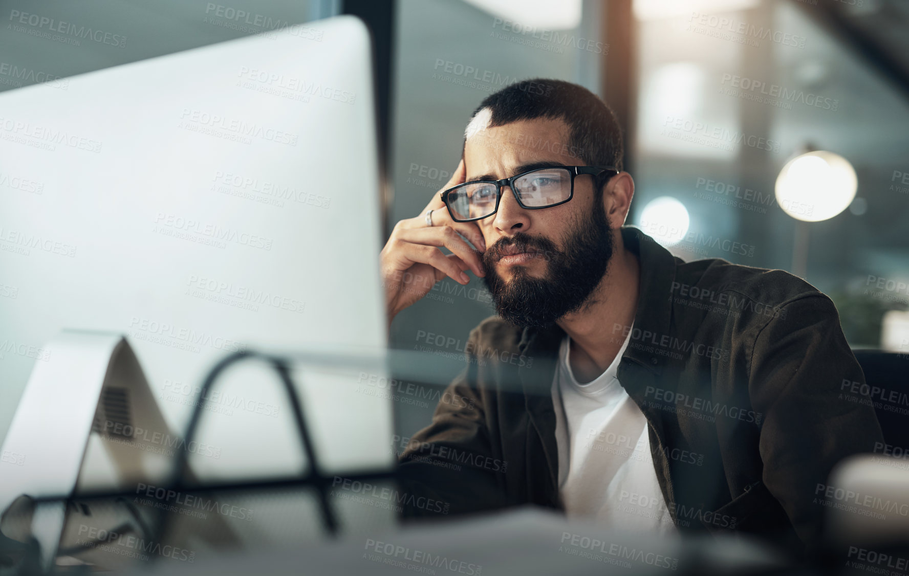 Buy stock photo Shot of a young businessman using a computer during a late night in a modern office