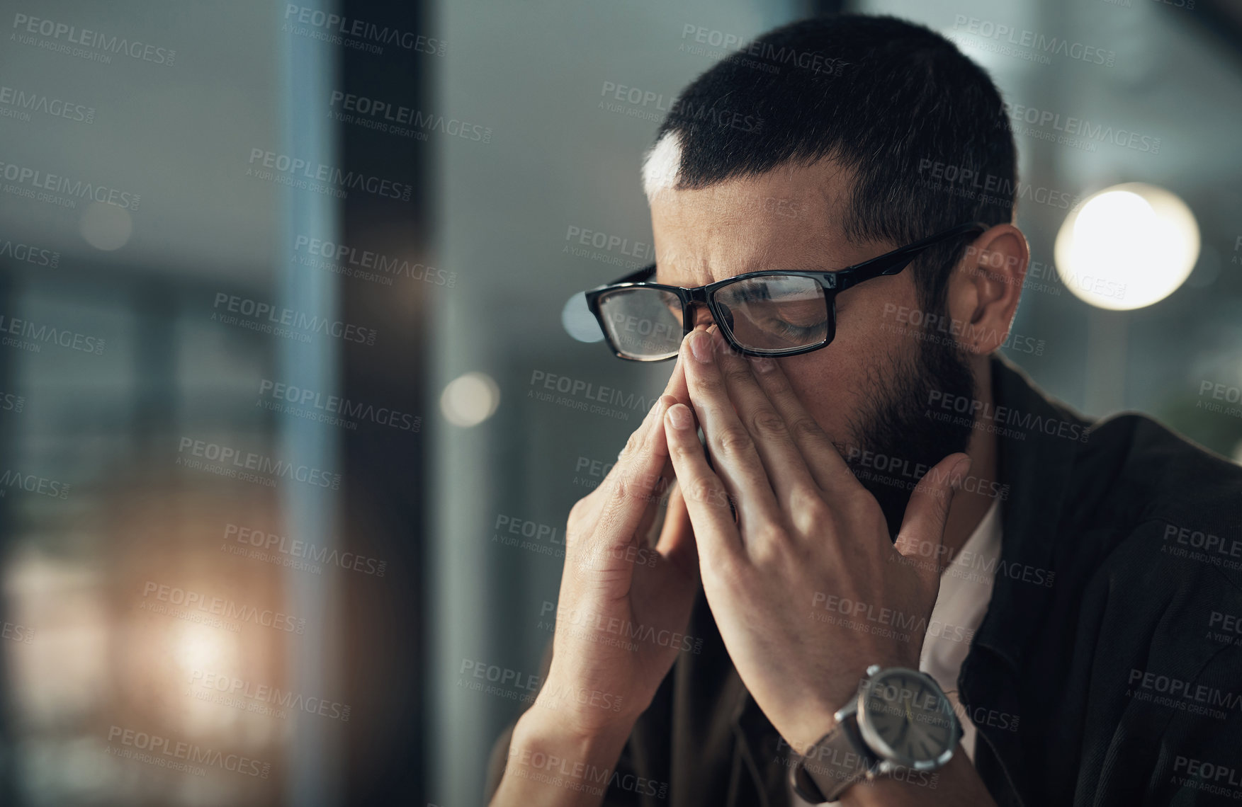 Buy stock photo Shot of a young businessman feeling stressed while working late at night in a modern office