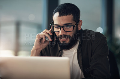 Buy stock photo Shot of a young businessman using a laptop and smartphone during a late night in a modern office