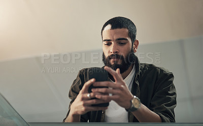 Buy stock photo Shot of a young businessman using a smartphone during a late night in a modern office