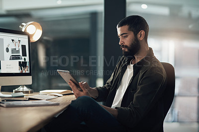 Buy stock photo Shot of a young businessman using a digital tablet during a late night in a modern office