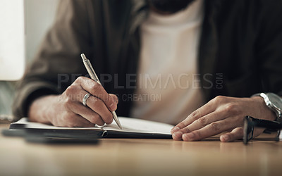 Buy stock photo Shot of an unrecognisable businessman writing in a notebook during a late night at work