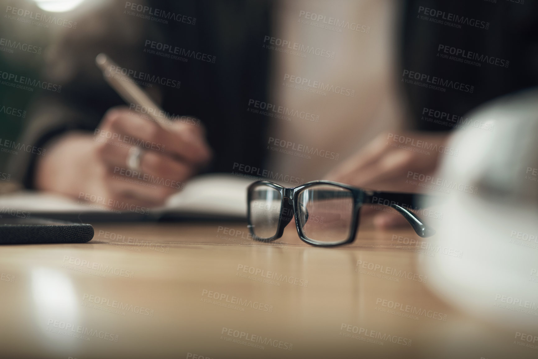 Buy stock photo Shot of an unrecognisable businessman writing in a notebook during a late night at work