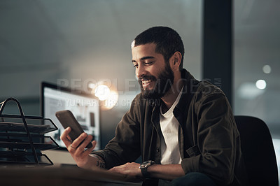 Buy stock photo Shot of a young businessman using a smartphone during a late night at work