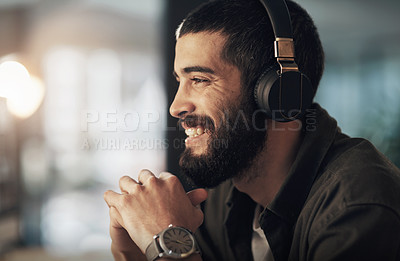 Buy stock photo Shot of a young businessman using headphones during a late night at work