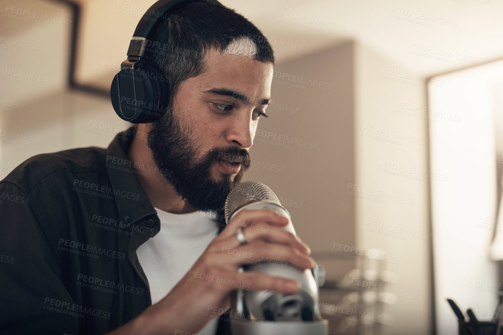 Buy stock photo Shot of a young man using a headset and microphone during a late night at work