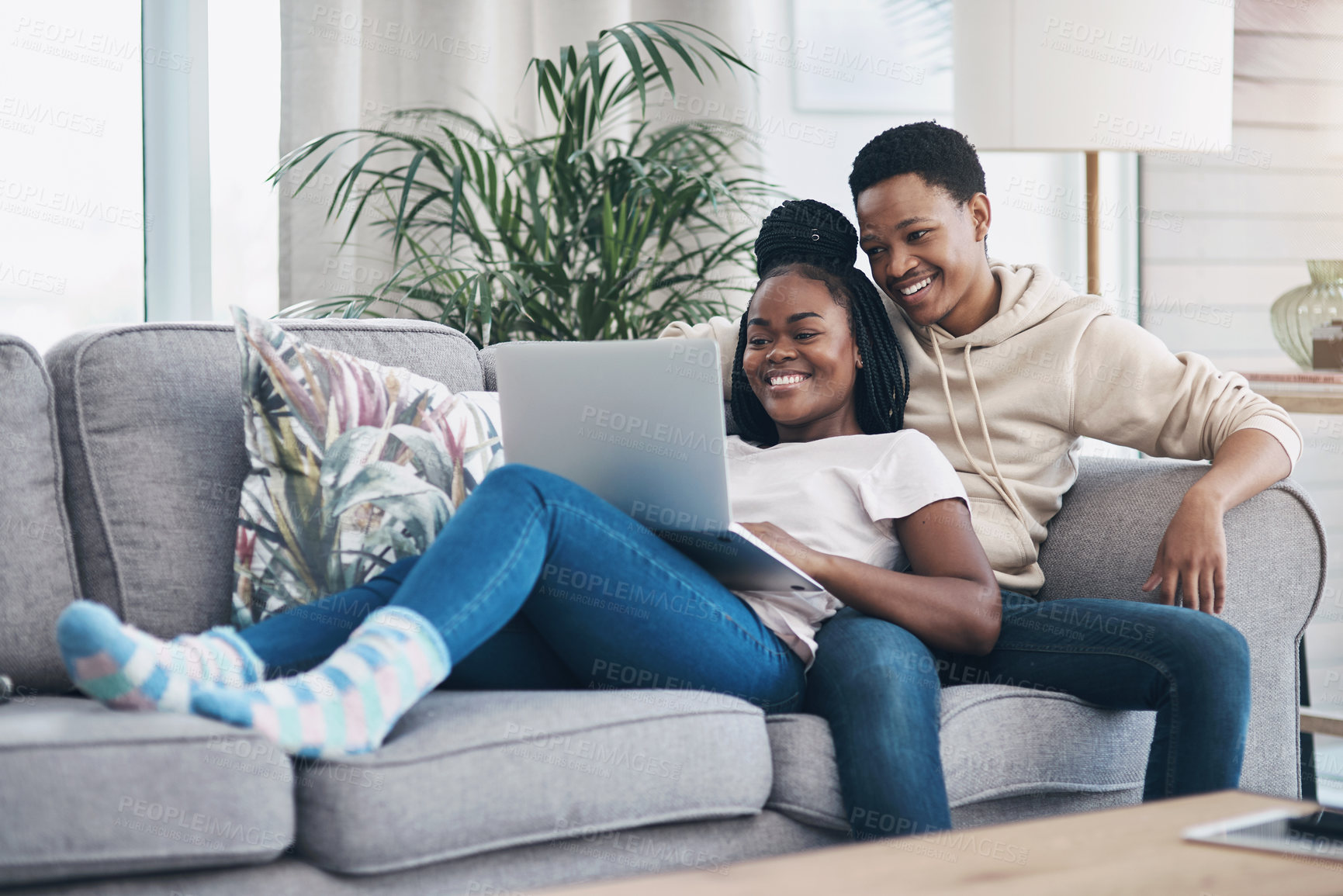 Buy stock photo Shot of a young couple using a laptop while relaxing on the sofa at home