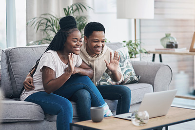 Buy stock photo Shot of a young couple using a laptop to make a video call on the sofa at home