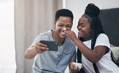 Buy stock photo Shot of a young couple taking selfies while getting homemade facials together at home