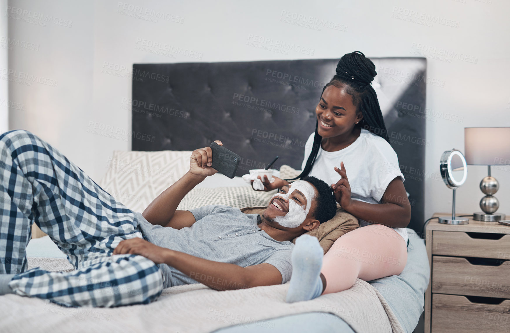 Buy stock photo Shot of a young couple taking selfies while getting homemade facials together at home